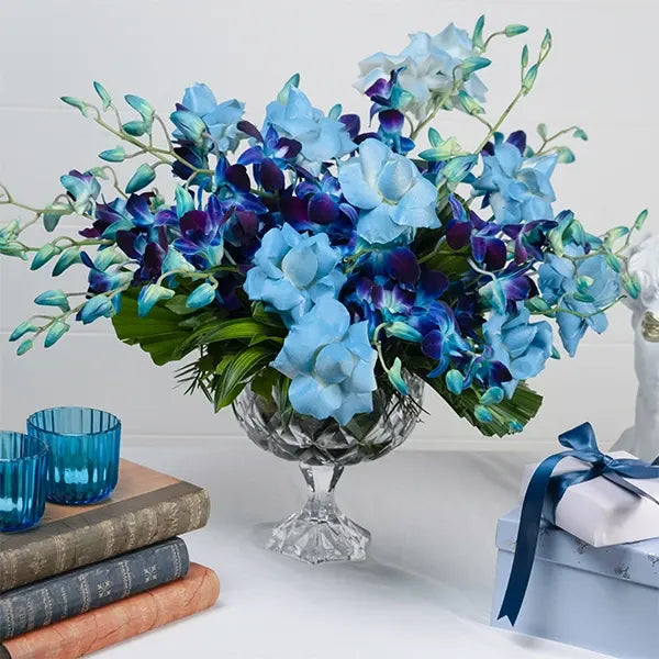 blue orchid and rose arrangement in crystal vase closeup view