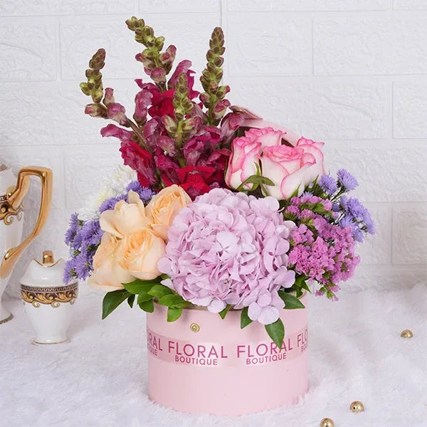 jumeila roses peach roses pink snap dragons in a light pink box closeup view