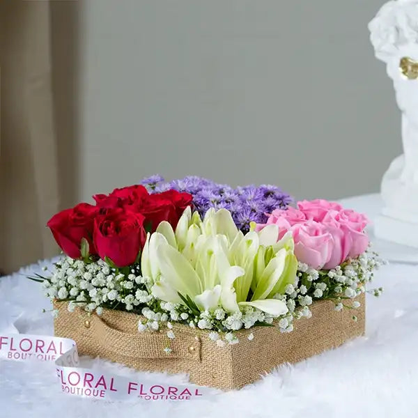 red revival roses blue daisies and lilies in a jute box front view