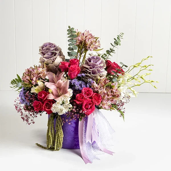 purple round flower box arrangement of dark pink roses and pink alstroemeria flowers close up view