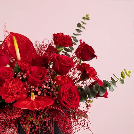 red flower box arrangement of 20 red roses with red carnations close up view