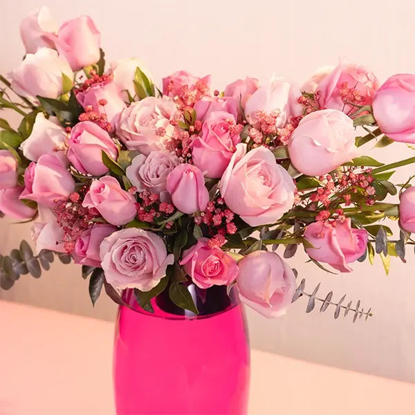 pink roses in a pink glass vase closeup view