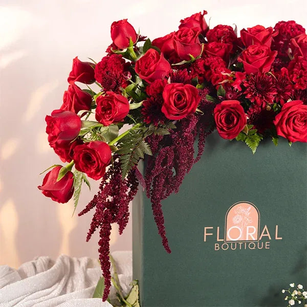a large green box filled with red roses celosia and chrysanthemums close up view 2