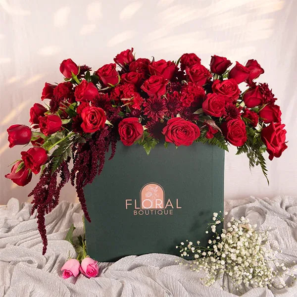 a large green box filled with red roses celosia and chrysanthemums front view 2