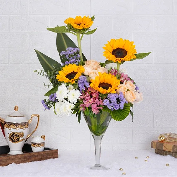sunflowers peach roses white chrysanthemums in a glass cone arrangement front view