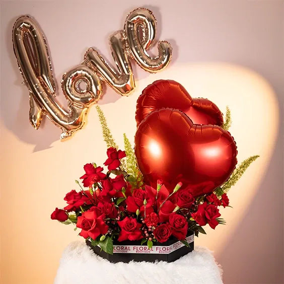 red rose and carnation arrangement in a box with two heart balloons front view 3
