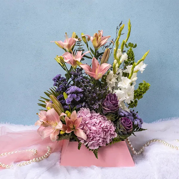 mixed flower box arrangement of pink asiatic lilies hydrangea barcia purple white glads blue daisies close up view