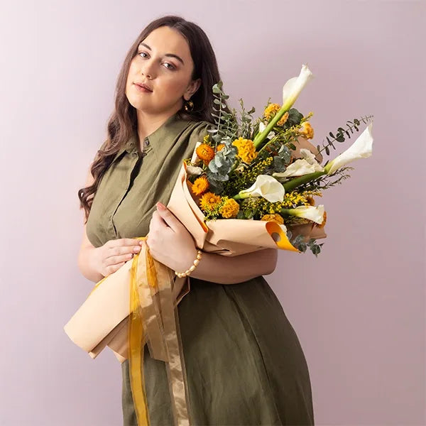 lily bouquet with yellow celosia white carnations wrapped in brown paper front view 2
