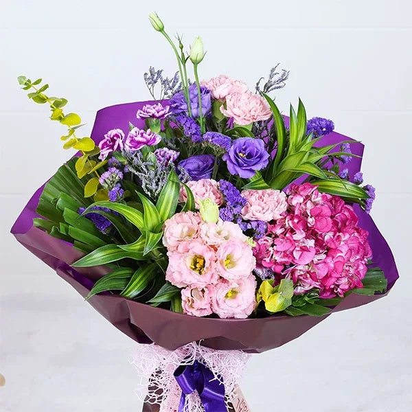 hydrangea and carnation bouquet in purple wrapping paper closeup view
