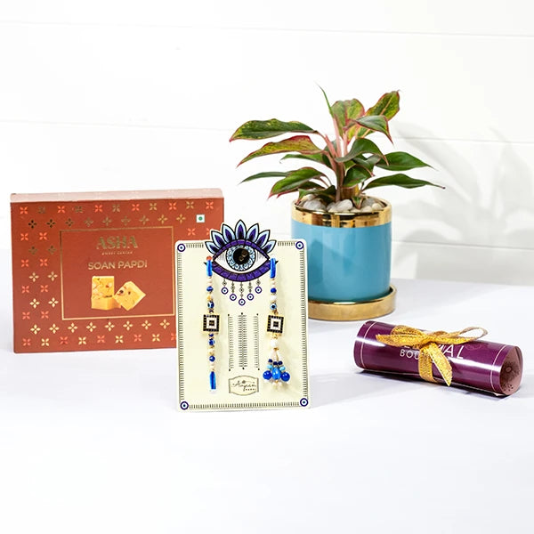evil eye rakhi lumba hamper with soan papdi aglaonema in blue ceramic pot front view