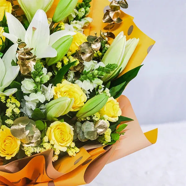 white asiatic lilies and yellow roses bouquet in yellow dot paper close up view