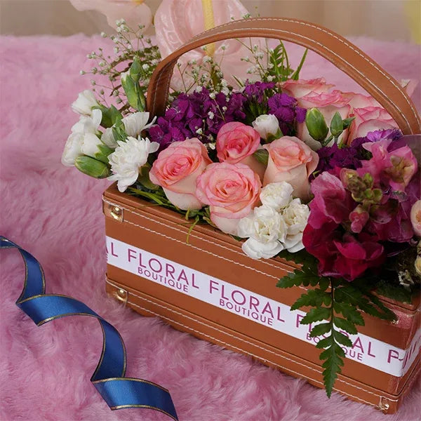 jumelia roses pink anthurium dark pink snapdragons in leather basket close up view