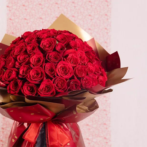 100 red roses bouquet wrapped in red and gold paper close up view