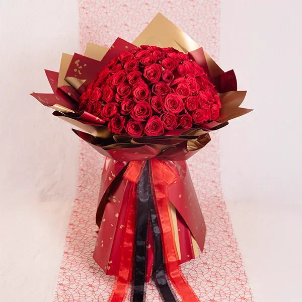 100 red roses bouquet wrapped in red and gold paper front view