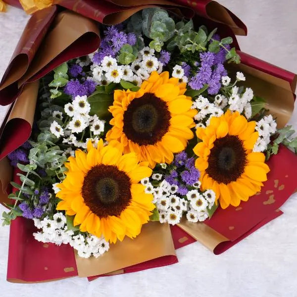 mixed flower bouquet of sunflowers white santon and blue daisies front view