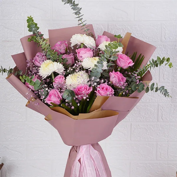 pink and white bouquet of pink roses wrapped in pale pink paper close up view