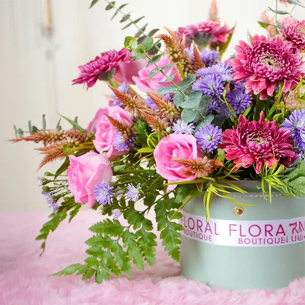 a round leather box filled with a mix of revival roses and mini gerberas close up view