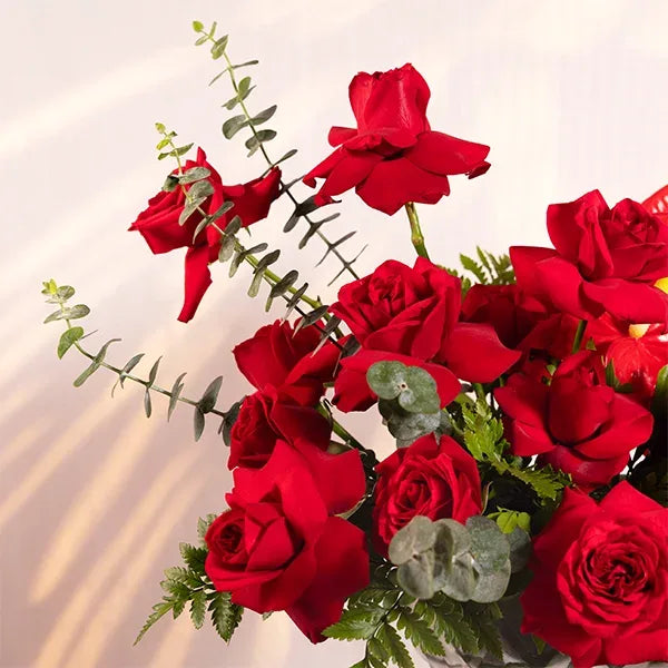 red roses and anthurium in a glass vase close up view