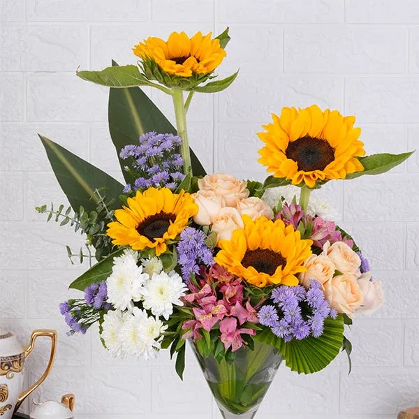 sunflowers peach roses white chrysanthemums in a glass cone arrangement close up view