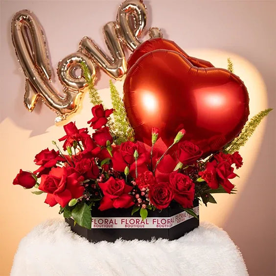red rose and carnation arrangement in a box with two heart balloonsfront view 2